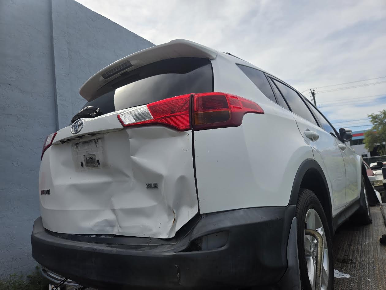 White Toyota RAV4 with rear collision damage prepared for flatbed pickup