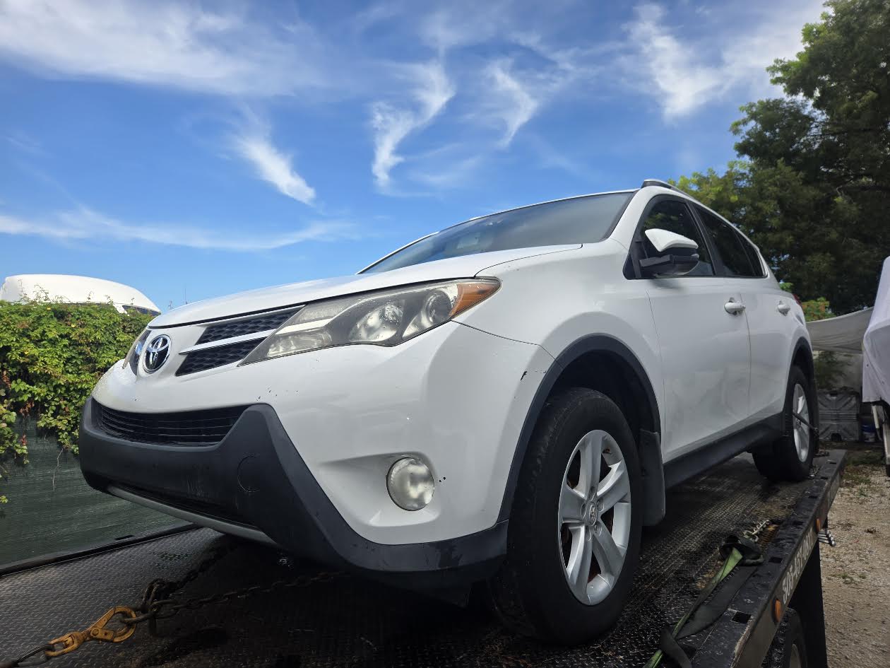 Front view of a white Toyota RAV4 prepared for flatbed transport