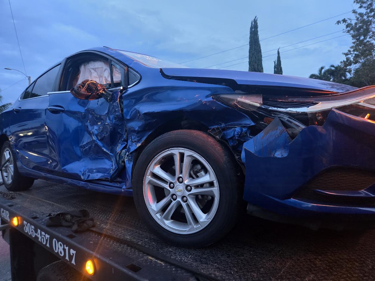 Blue Chevrolet Cruze with severe side collision damage on a flatbed